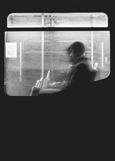 在波士顿，一张黑白照片，一名男子从肮脏的窗户坐在夜车上